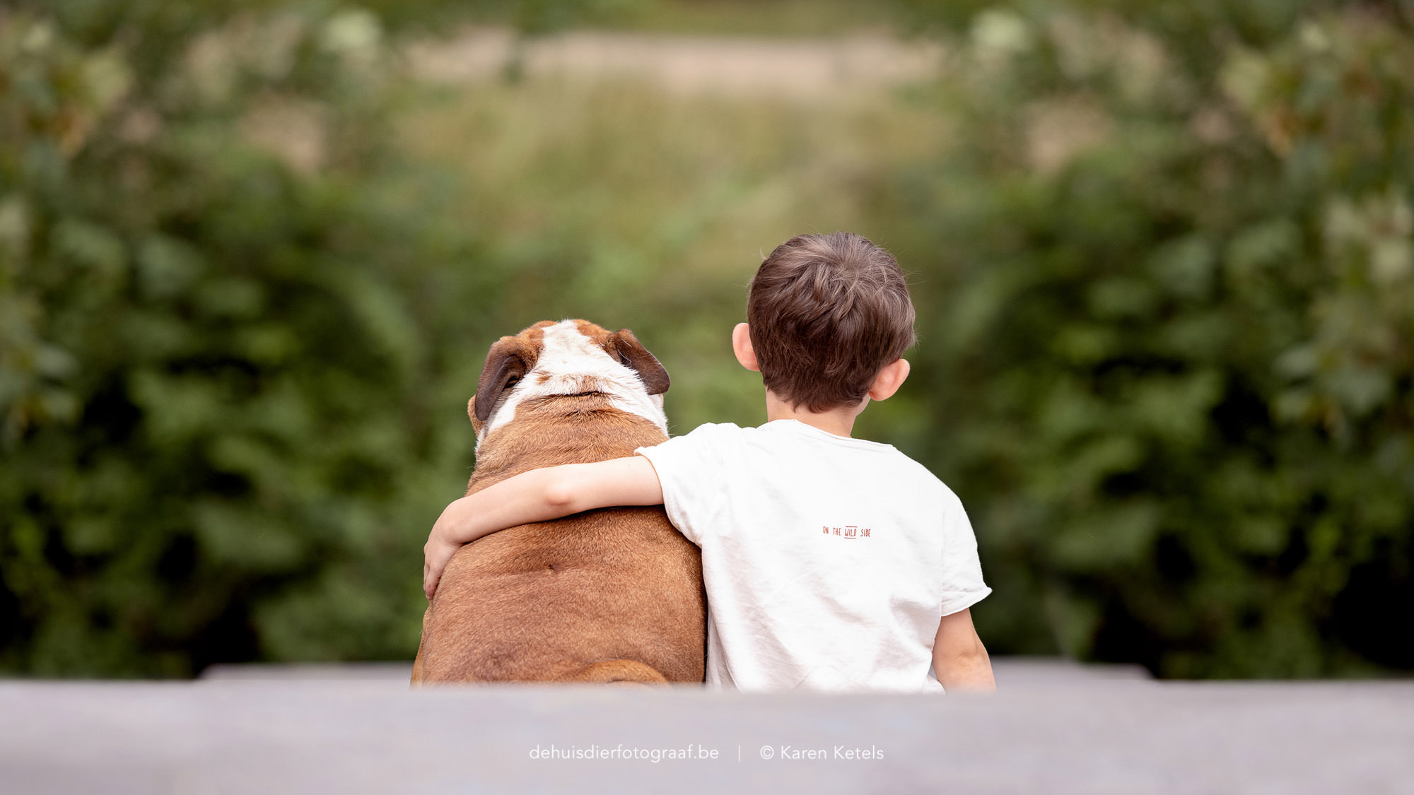 Portret van een jongen met zijn arm rond zijn beste vriend; een Engelse Bulldog. Portret door De Huisdierfotograaf